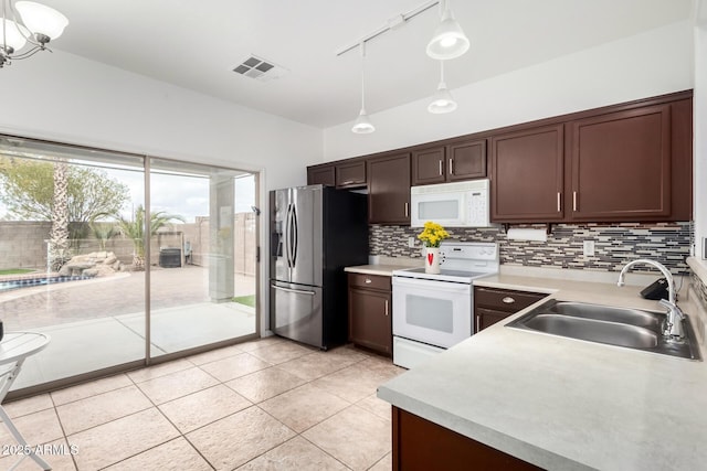 kitchen with white appliances, decorative light fixtures, sink, and backsplash