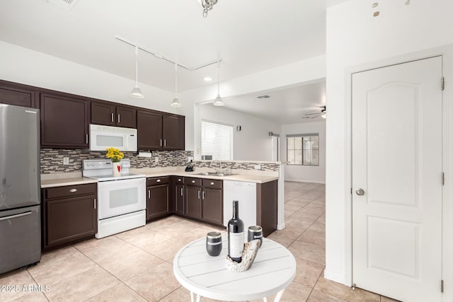 kitchen featuring sink, white appliances, light tile patterned floors, hanging light fixtures, and decorative backsplash