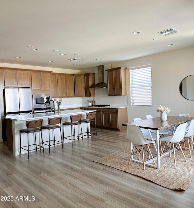 32040 N Lisadre Ln, San Tan Valley, AZ 85144 - kitchen featuring appliances with stainless steel finishes, wall chimney range hood, light wood-style floors, an island with sink, and recessed lighting