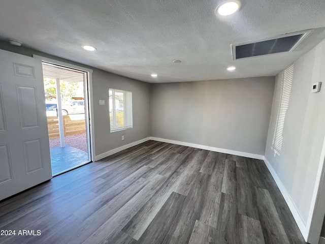 spare room featuring dark wood-type flooring and a textured ceiling