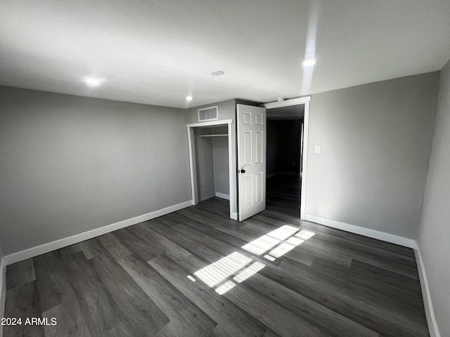 unfurnished bedroom with dark hardwood / wood-style floors and a closet