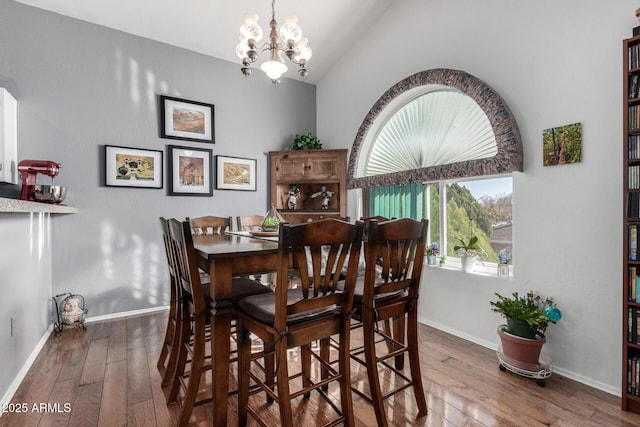 dining space featuring vaulted ceiling, dark wood-type flooring, a chandelier, and baseboards