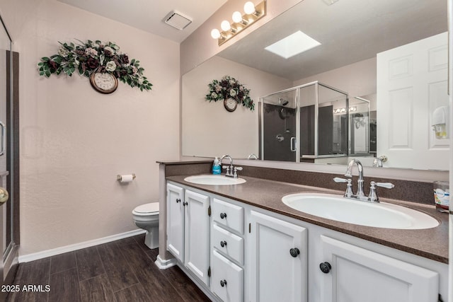 bathroom featuring double vanity, toilet, a sink, and wood finished floors