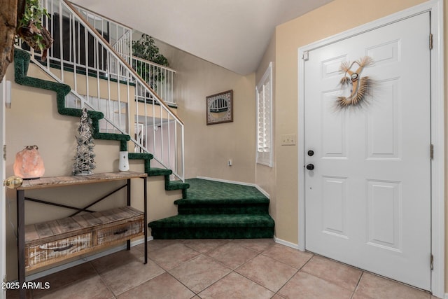 tiled entrance foyer featuring stairs, vaulted ceiling, and baseboards