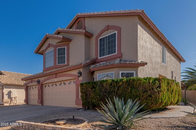 mediterranean / spanish-style house with concrete driveway, an attached garage, a tile roof, and stucco siding