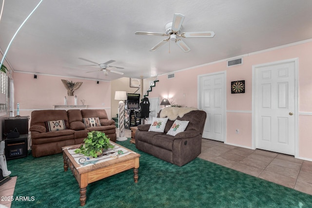 tiled living room with crown molding, visible vents, ceiling fan, and stairway