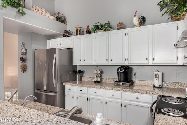 kitchen featuring a sink, freestanding refrigerator, and white cabinets