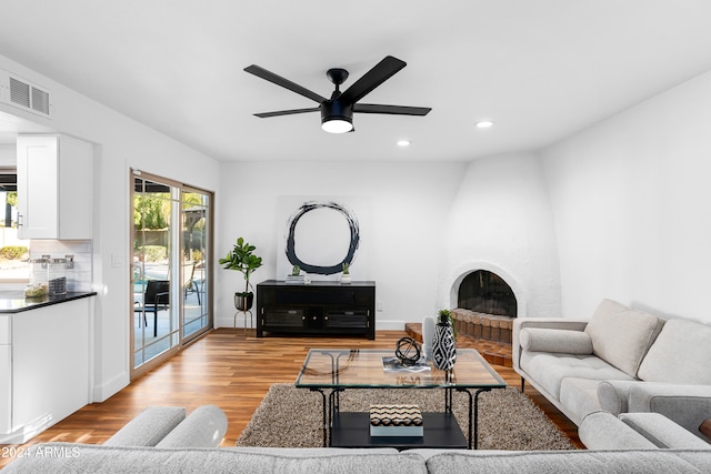 living room featuring light wood-type flooring, ceiling fan, and a fireplace