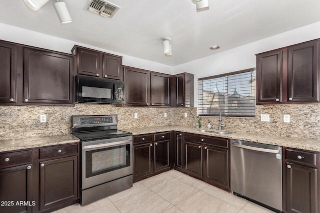 kitchen with appliances with stainless steel finishes, tasteful backsplash, sink, light tile patterned floors, and dark brown cabinets