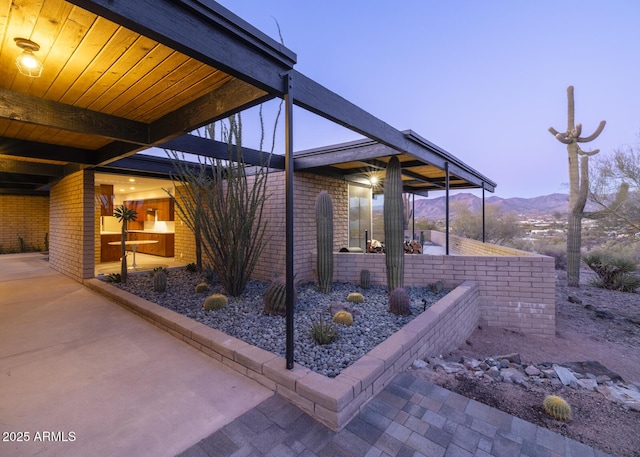 patio terrace at dusk featuring a carport and a mountain view