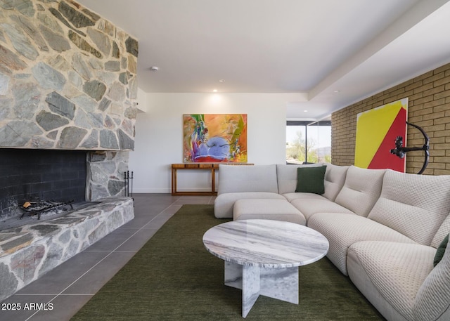 living room featuring dark tile patterned flooring and a stone fireplace