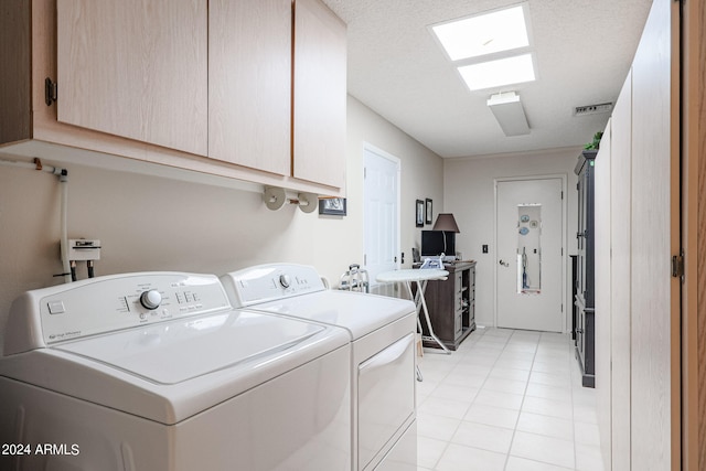 laundry area featuring light tile patterned flooring, washing machine and dryer, and cabinets