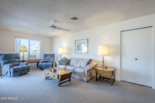 living room featuring carpet, ceiling fan, and a textured ceiling