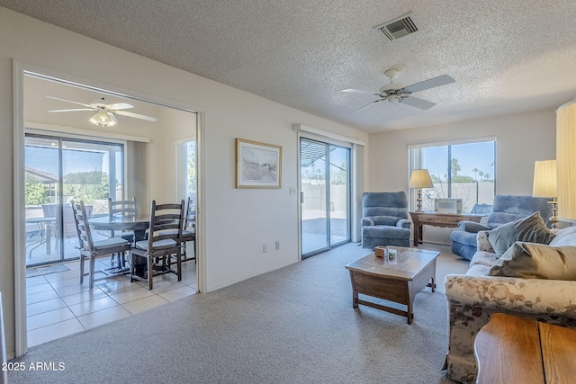 living room featuring light carpet, plenty of natural light, ceiling fan, and a textured ceiling