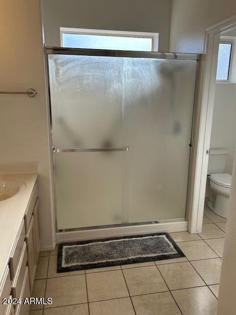 bathroom with tile patterned floors, vanity, an enclosed shower, and toilet