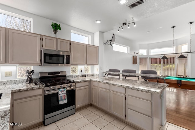 kitchen with kitchen peninsula, plenty of natural light, billiards, and appliances with stainless steel finishes