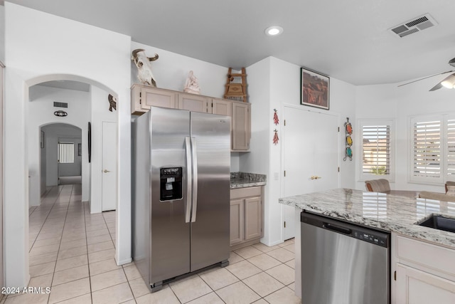 kitchen with ceiling fan, light stone counters, light tile patterned floors, and appliances with stainless steel finishes