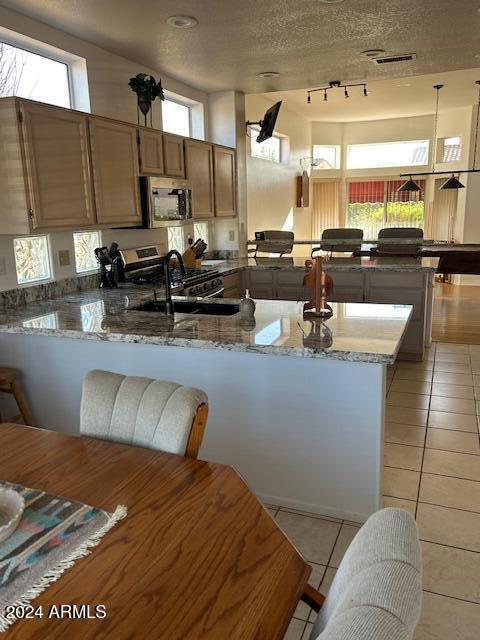 kitchen featuring kitchen peninsula, pendant lighting, a textured ceiling, and a healthy amount of sunlight