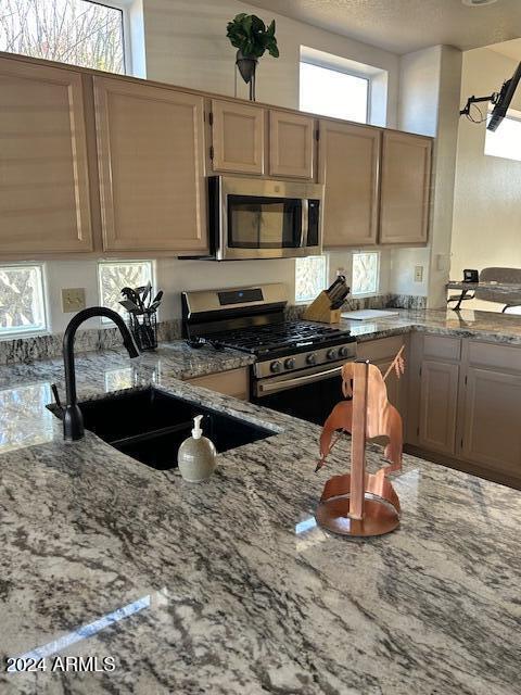 kitchen with light stone countertops, sink, and appliances with stainless steel finishes