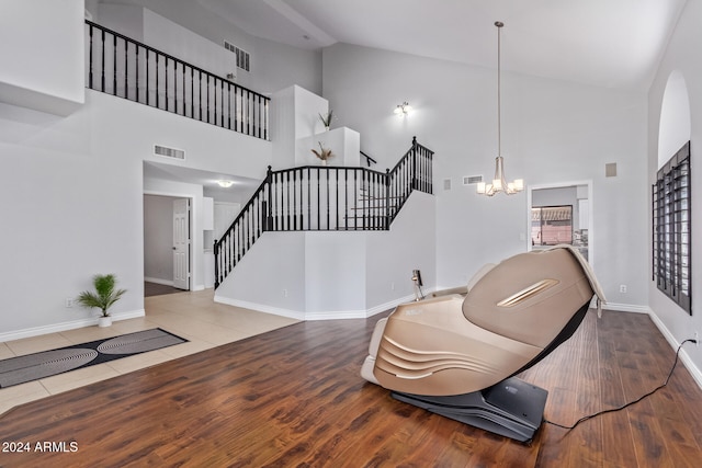 sitting room with hardwood / wood-style flooring, high vaulted ceiling, and an inviting chandelier