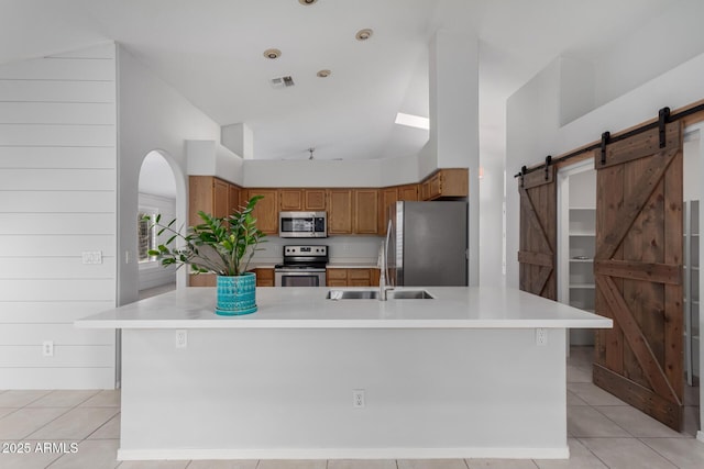 kitchen featuring a barn door, visible vents, appliances with stainless steel finishes, and a sink