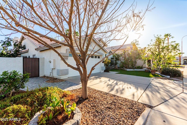 exterior space featuring stucco siding, a tile roof, concrete driveway, and fence