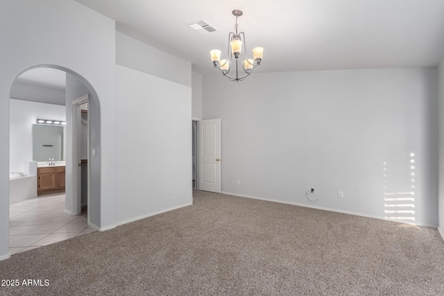 spare room featuring arched walkways, visible vents, light colored carpet, and a sink