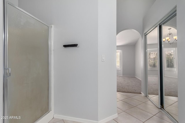 bathroom featuring tile patterned flooring, a shower stall, and baseboards