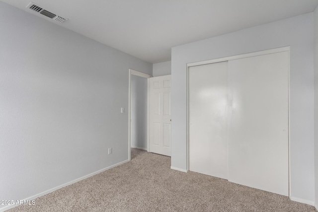 unfurnished bedroom featuring visible vents, baseboards, light colored carpet, and a closet