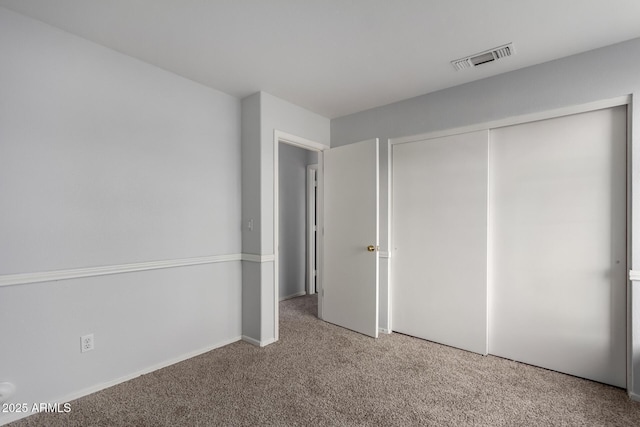 unfurnished bedroom featuring a closet, visible vents, and carpet flooring