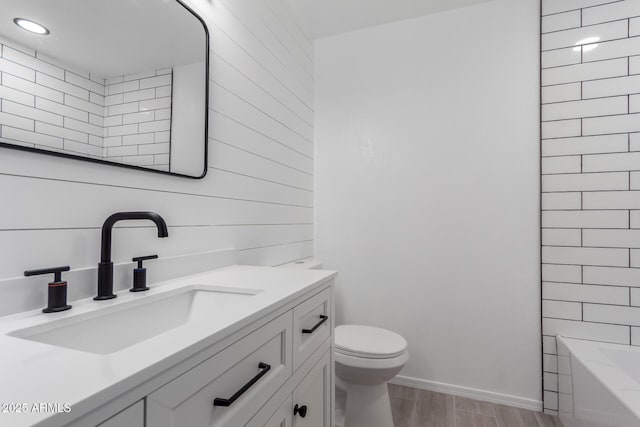 full bathroom with baseboards, toilet, wood finished floors, and vanity