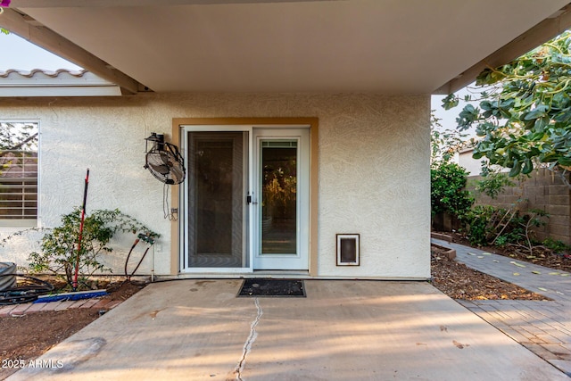 property entrance featuring stucco siding, a patio, and fence