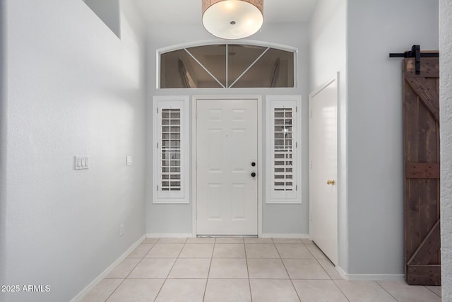 entryway with light tile patterned floors, baseboards, and a barn door