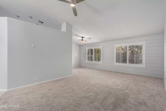 spare room featuring visible vents, carpet floors, ceiling fan, and wood walls