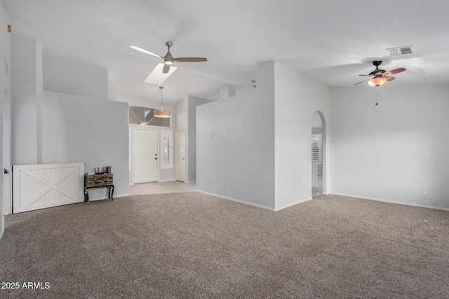 carpeted empty room with high vaulted ceiling, arched walkways, visible vents, and ceiling fan