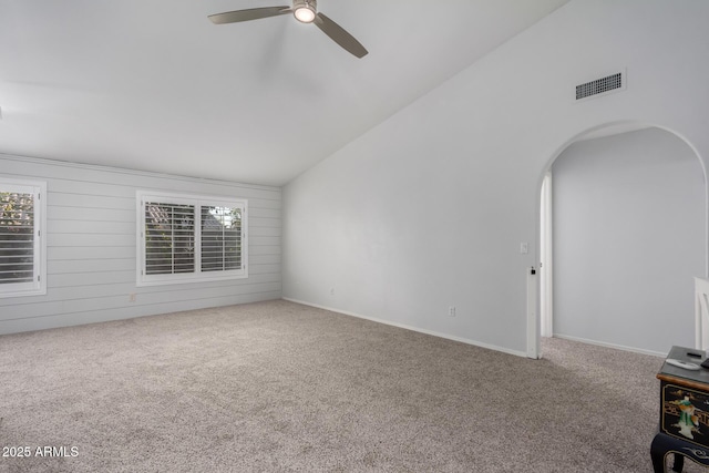 unfurnished room featuring arched walkways, visible vents, a wealth of natural light, and carpet