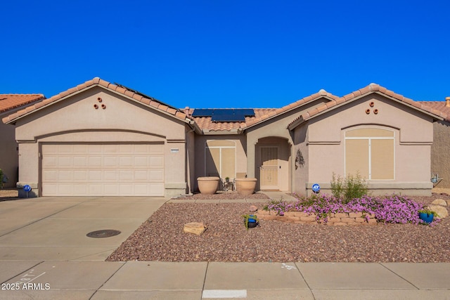 mediterranean / spanish-style home with solar panels, a tiled roof, concrete driveway, stucco siding, and a garage