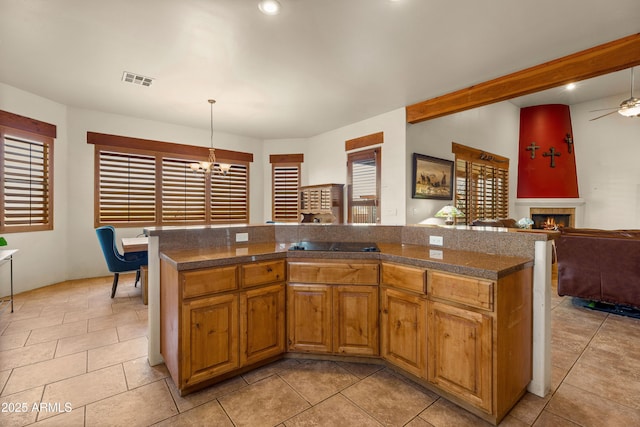 kitchen with hanging light fixtures, tile countertops, open floor plan, a lit fireplace, and visible vents