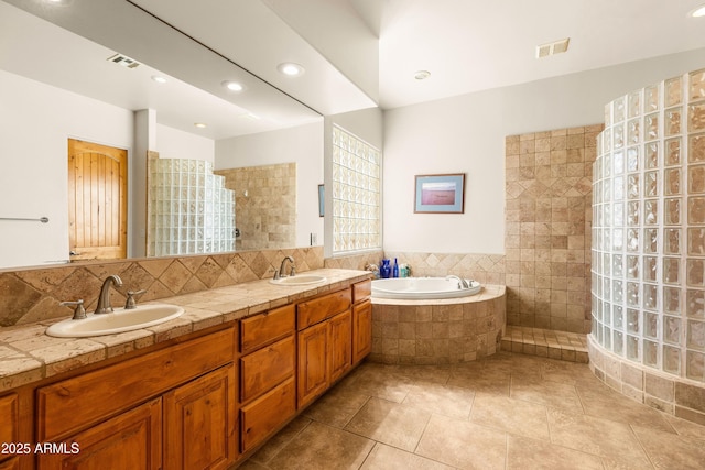 bathroom with a bath, walk in shower, visible vents, and a sink