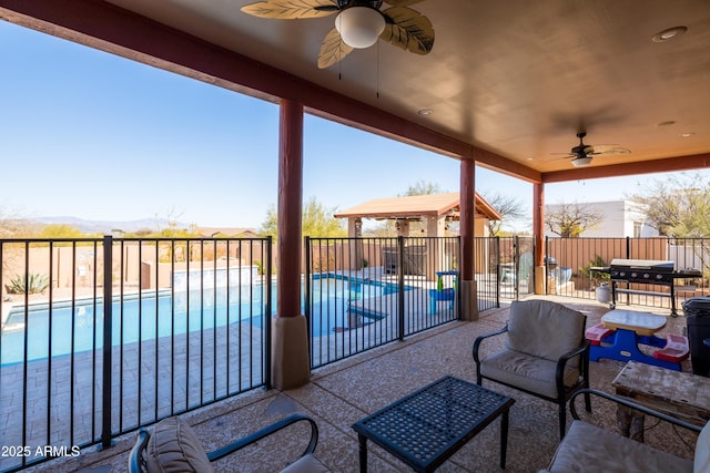 view of patio with grilling area, fence, a fenced in pool, and ceiling fan