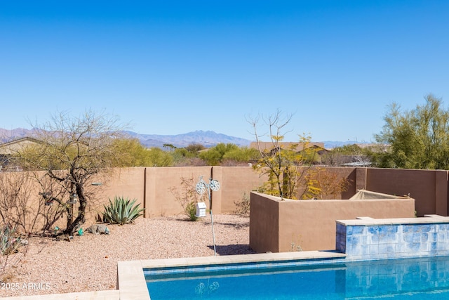 view of swimming pool featuring a fenced in pool, a fenced backyard, and a mountain view