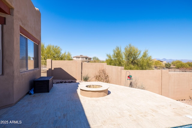 view of patio with a fire pit, fence, and a mountain view