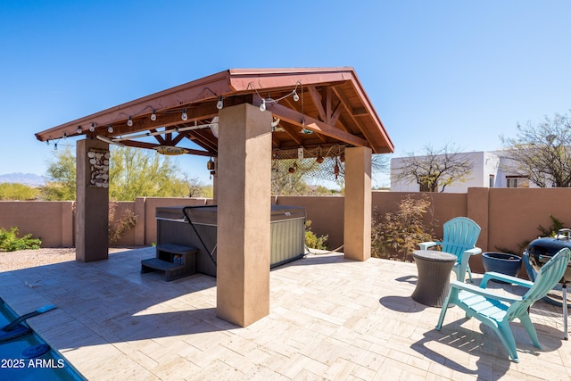 view of patio / terrace featuring a gazebo, a hot tub, and a fenced backyard