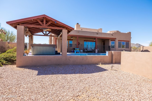 rear view of house with stucco siding, fence, a patio area, and a gazebo