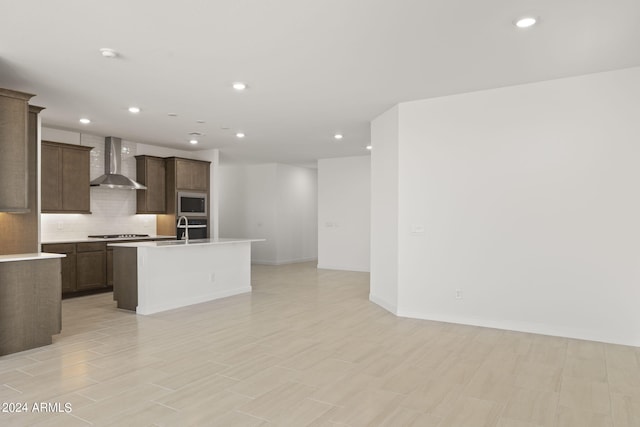 kitchen with wall chimney range hood, recessed lighting, open floor plan, and stainless steel microwave