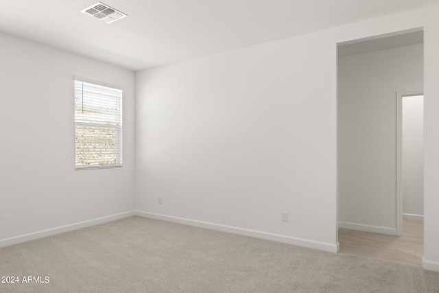 empty room with baseboards, visible vents, and light colored carpet