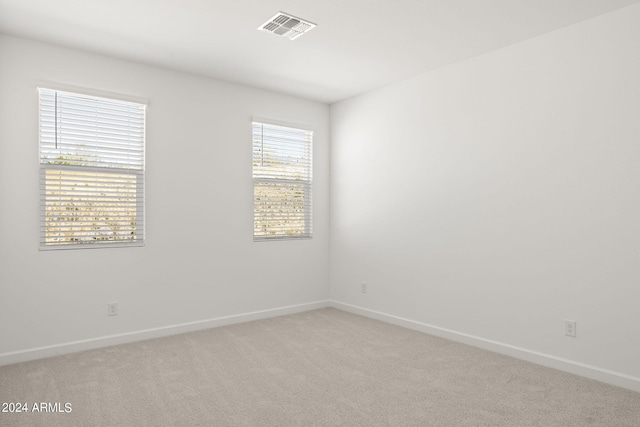 spare room featuring baseboards, visible vents, and light carpet