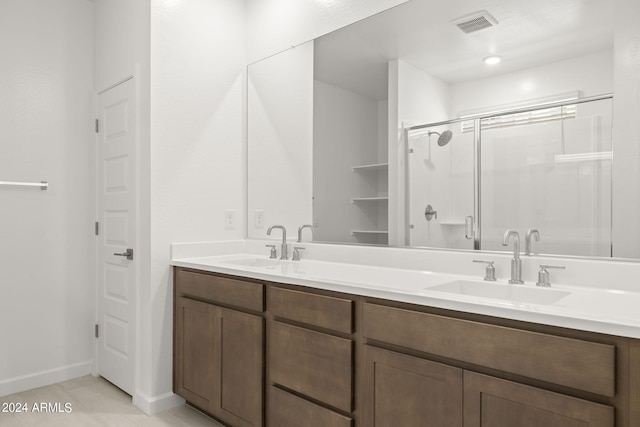 full bath with visible vents, a sink, double vanity, and a shower stall