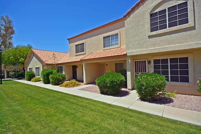 traditional-style house with a front lawn, stucco siding, and a tile roof