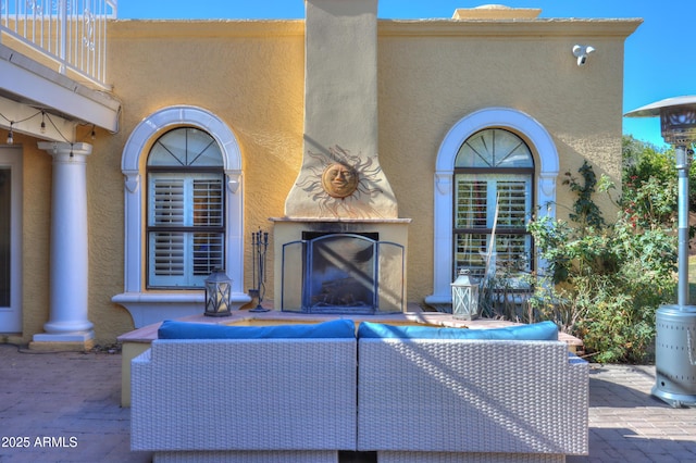 view of patio / terrace with an outdoor living space with a fireplace and a balcony